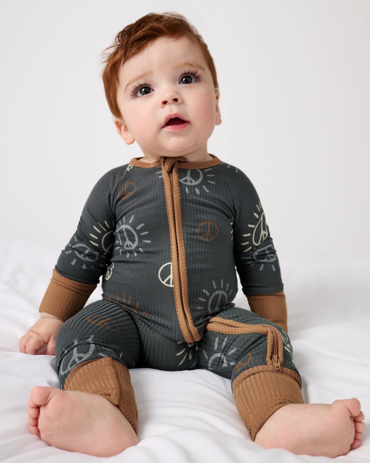 Sitting baby wearing the Peace & Love Ribbed Zippy