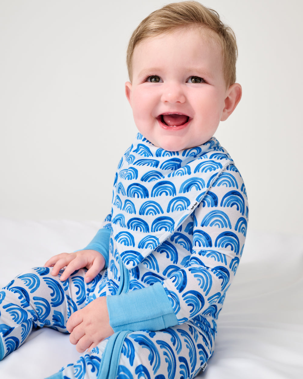 Baby wearing the Blue Rainbows Bandana Bib and Zippy
