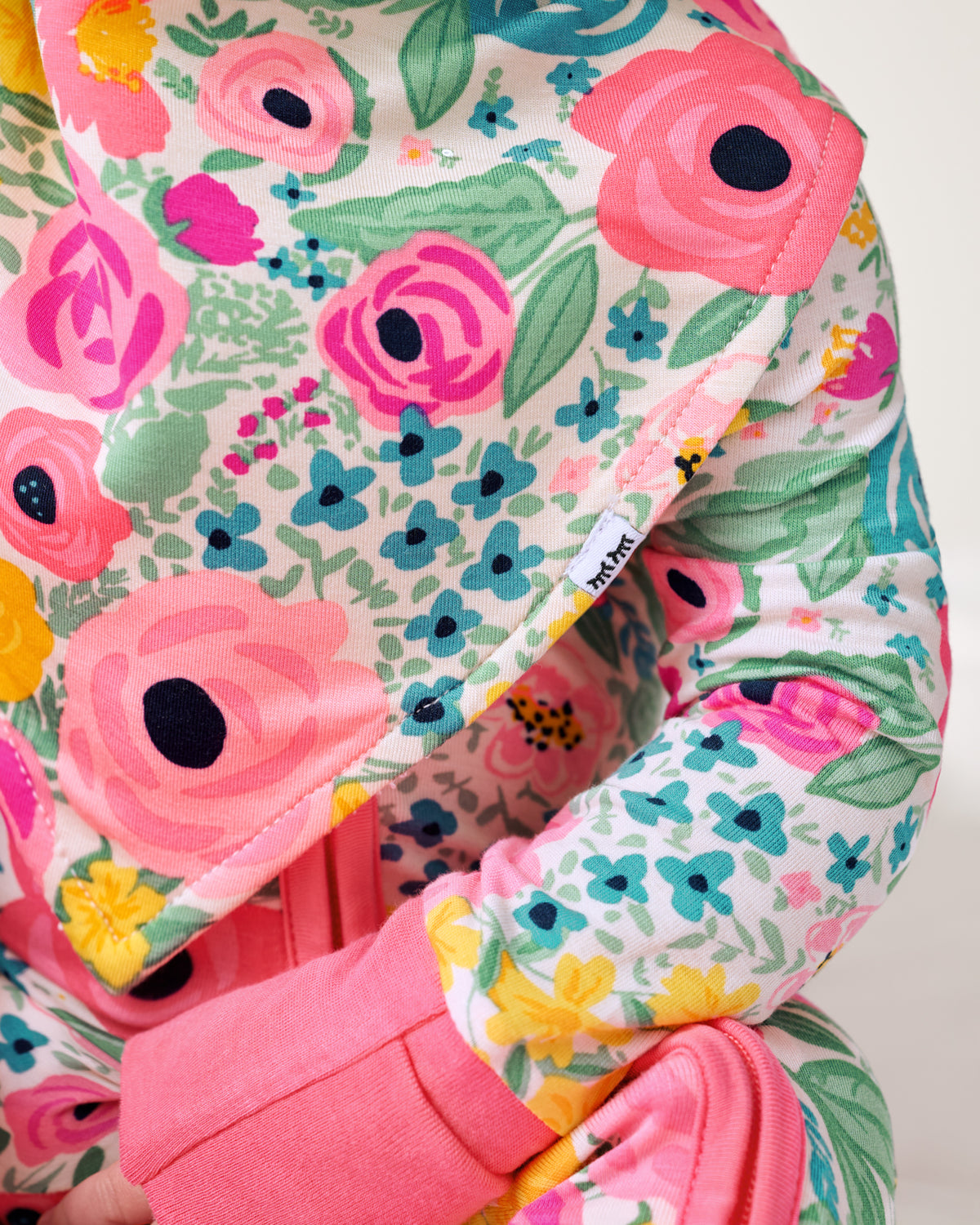 Close up of the Little Sleepies logo on the Secret Garden Bandana Bib