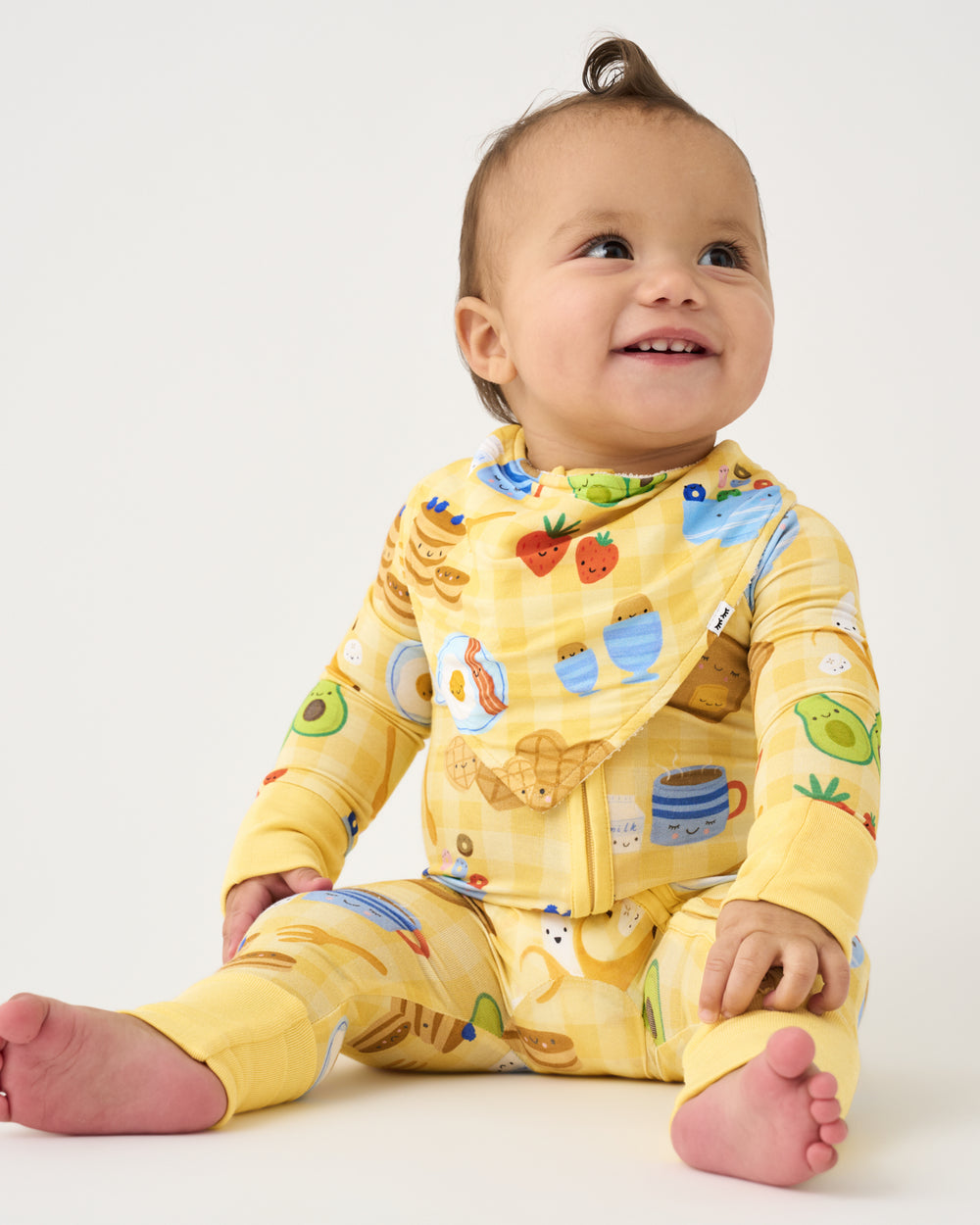 Sitting baby wearing the Breakfast Bunch Bandana Bib and Zippy