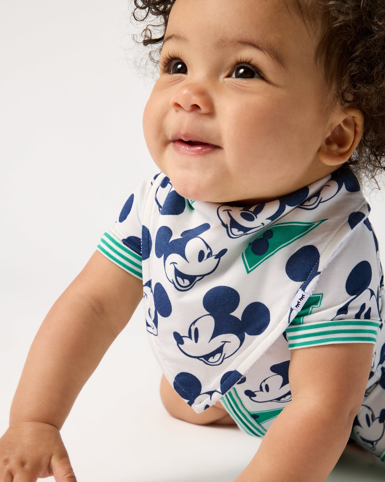 Close up of baby wearing the Disney Varsity Mickey Mouse Bandana Bib
