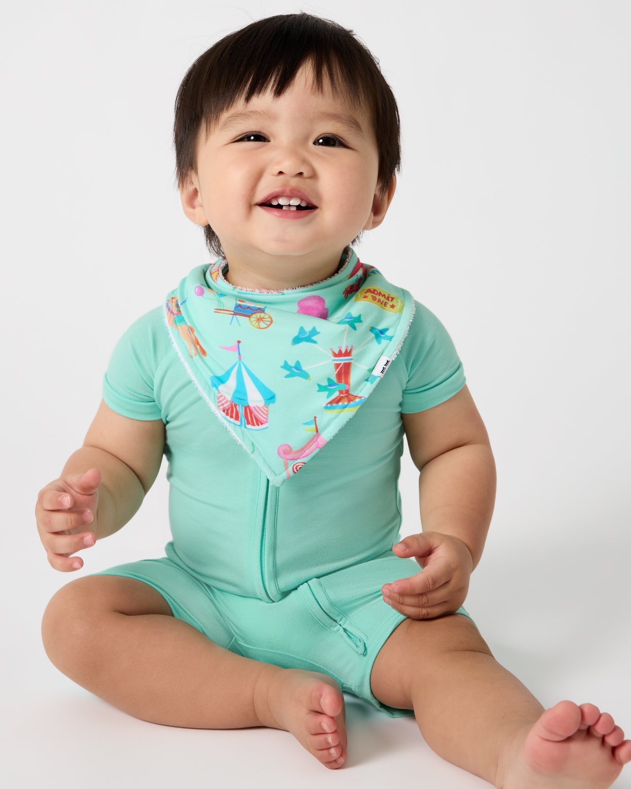 Baby wearing the Fizzy Fair Bandana Bib with the Ocean Mist Shorty ZIppy