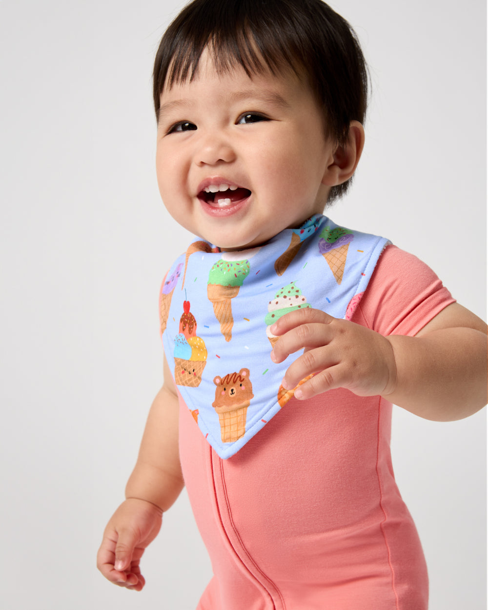 Baby wearing the Scoop Squad Bandana Bib with a salmon zipper pajama