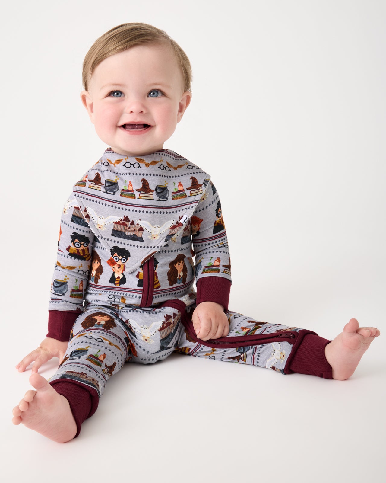 Sitting baby wearing the Harry Potter™ Spellbinding Studies Bandana Bib with a matching zippy