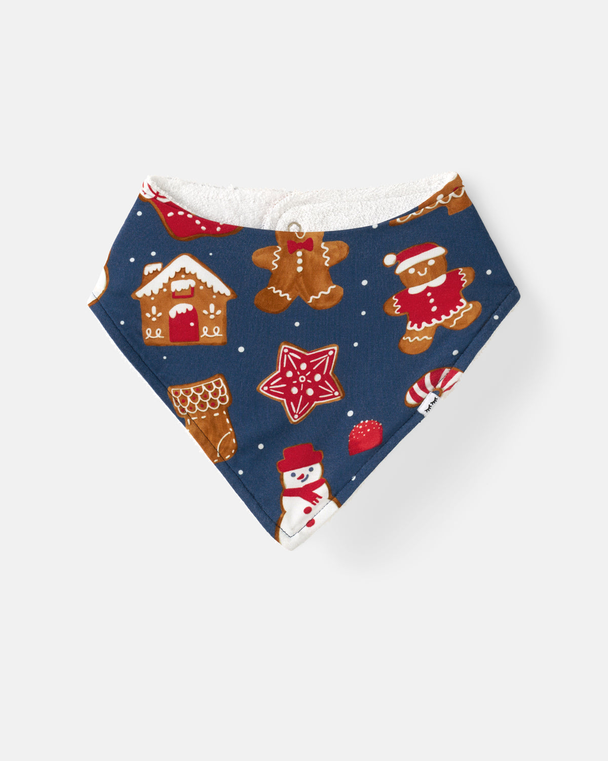 A triangular baby bandana bib with a festive Christmas print on a navy blue background, featuring gingerbread men, houses, snowmen, and candy canes, with a white backing.
