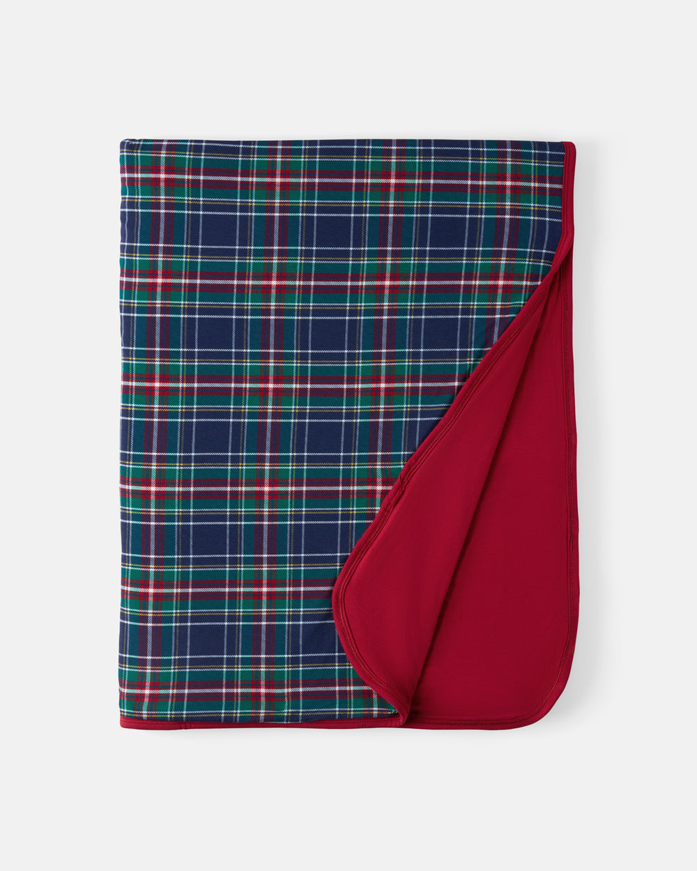 A folded blanket with a navy blue plaid pattern featuring red and green stripes, showing a solid deep red reverse side, set against a light gray background.