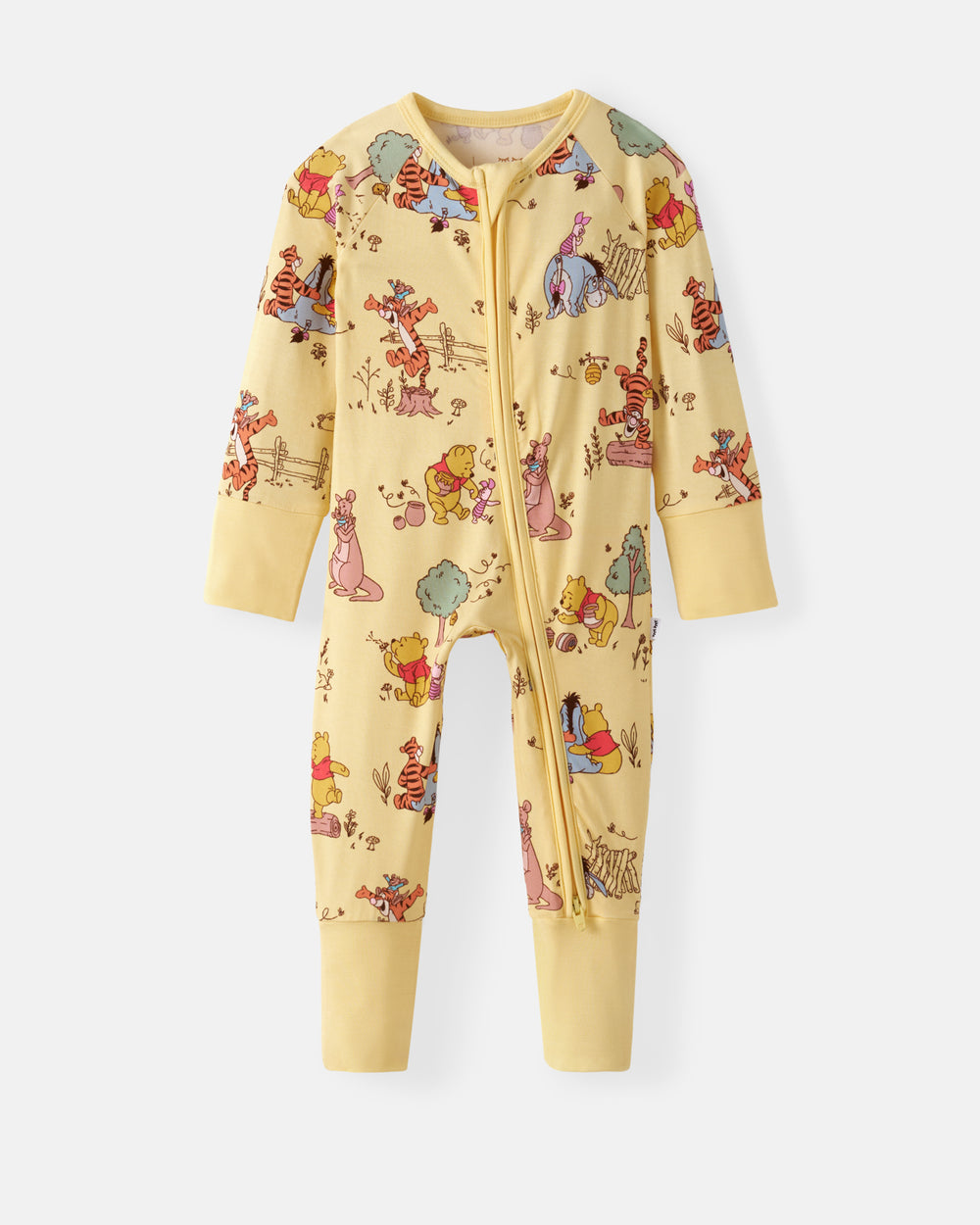 A baby long-sleeve zip-up footless one-piece pajama in a pale yellow color, featuring an all-over Winnie the Pooh print with characters like Winnie the Pooh, Tigger, and Eeyore, shown against a light gray background.