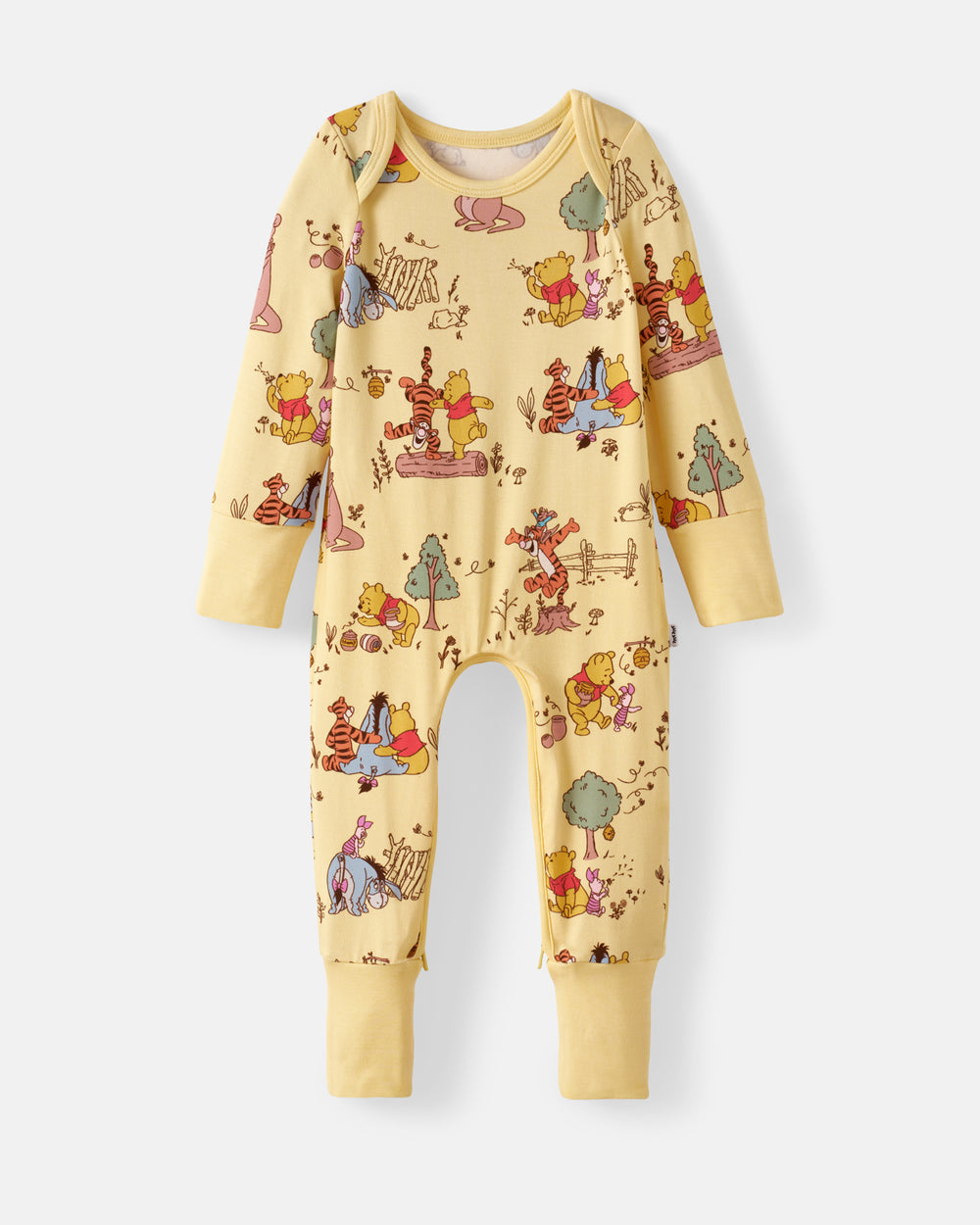A baby long-sleeve jumpsuit pajama in pale yellow with an all-over Winnie the Pooh print, shown flat against a light gray background.