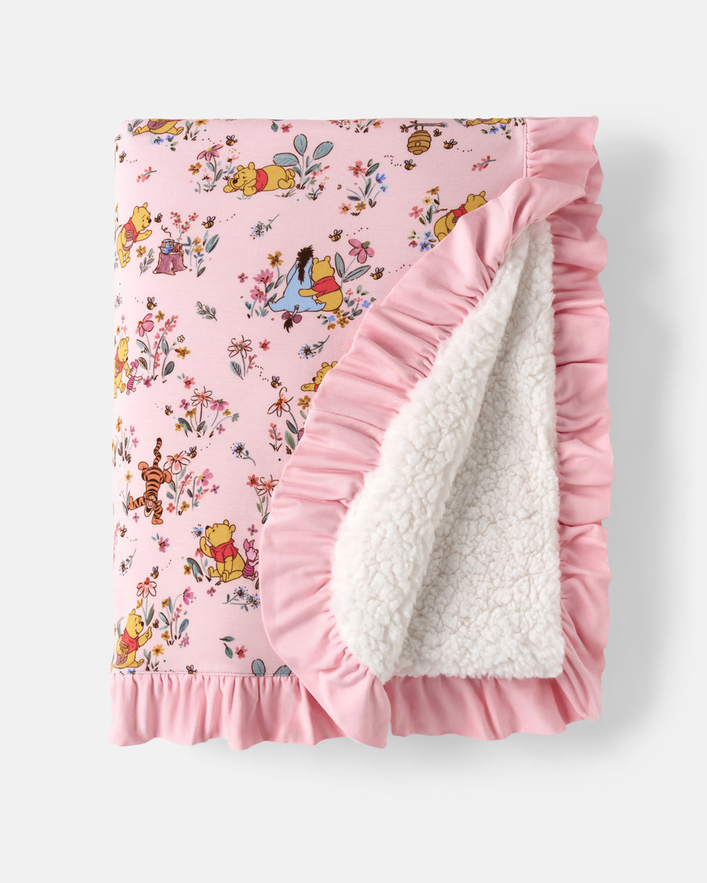 A pink fleece blanket featuring a Winnie the Pooh print on one side and a soft white sherpa lining on the other, finished with ruffled edges.
