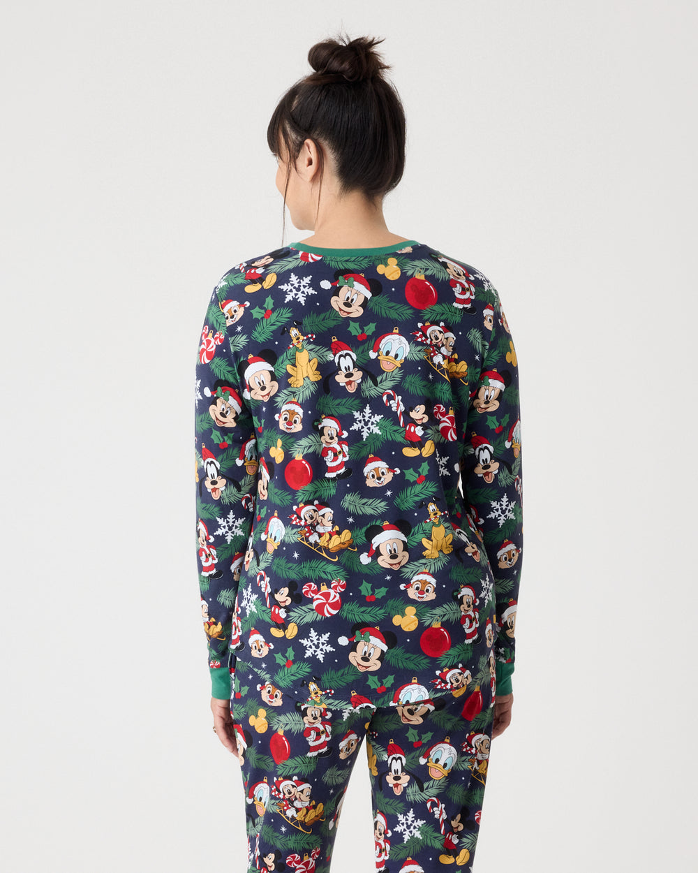 A model viewed from the back wearing a long-sleeve pajama set with a festive Disney character print on a dark blue background.
