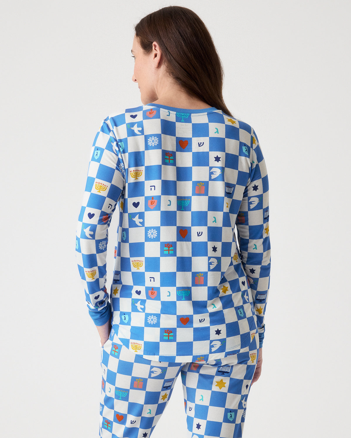 A woman shown from the back wearing a matching long-sleeve top and pants set in a blue and white checkerboard pattern with small multicolored symbols printed throughout, against a light gray studio background.