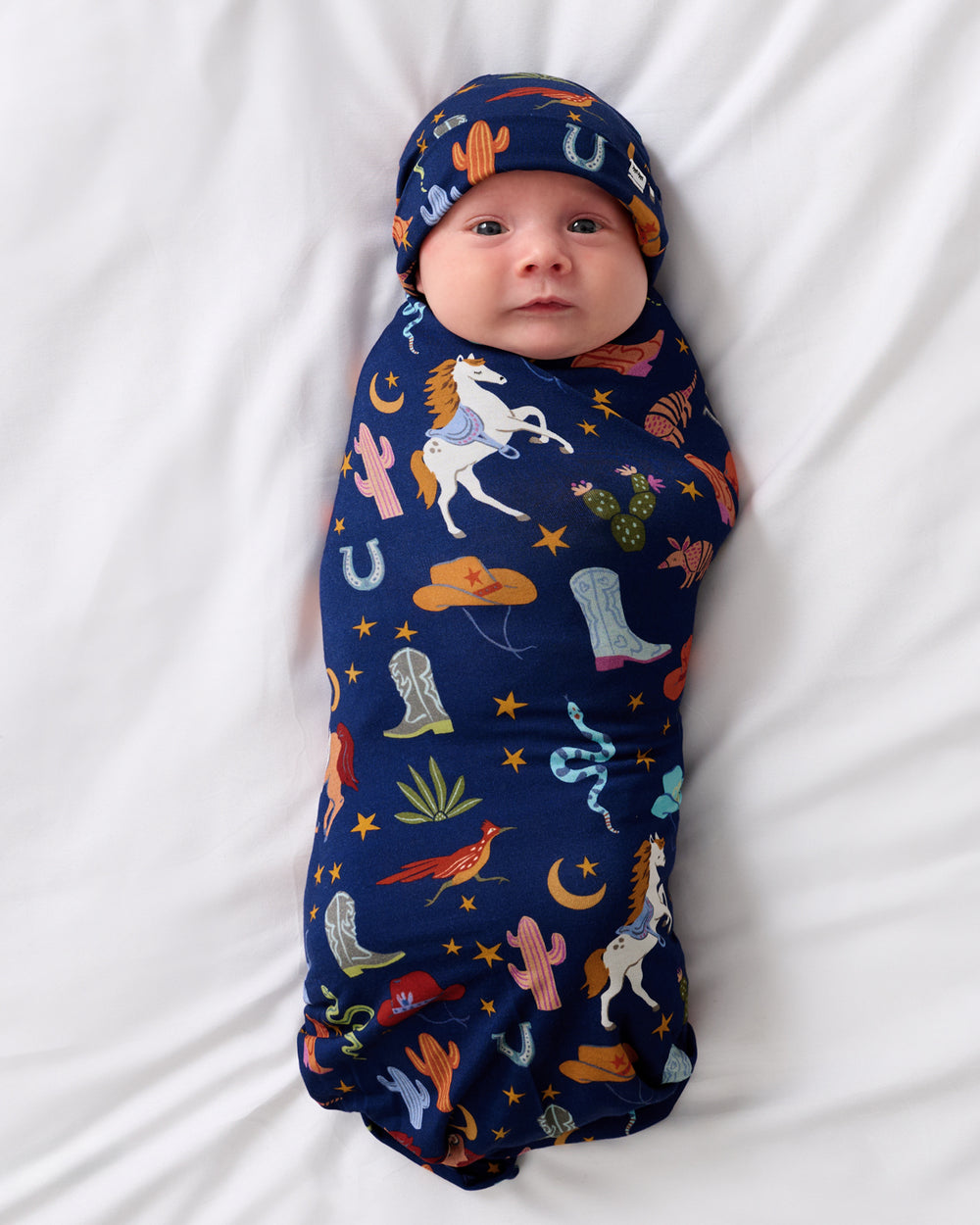 Aerial view of baby wearing the Blue Rancher Roundup Swaddle & Hat Set