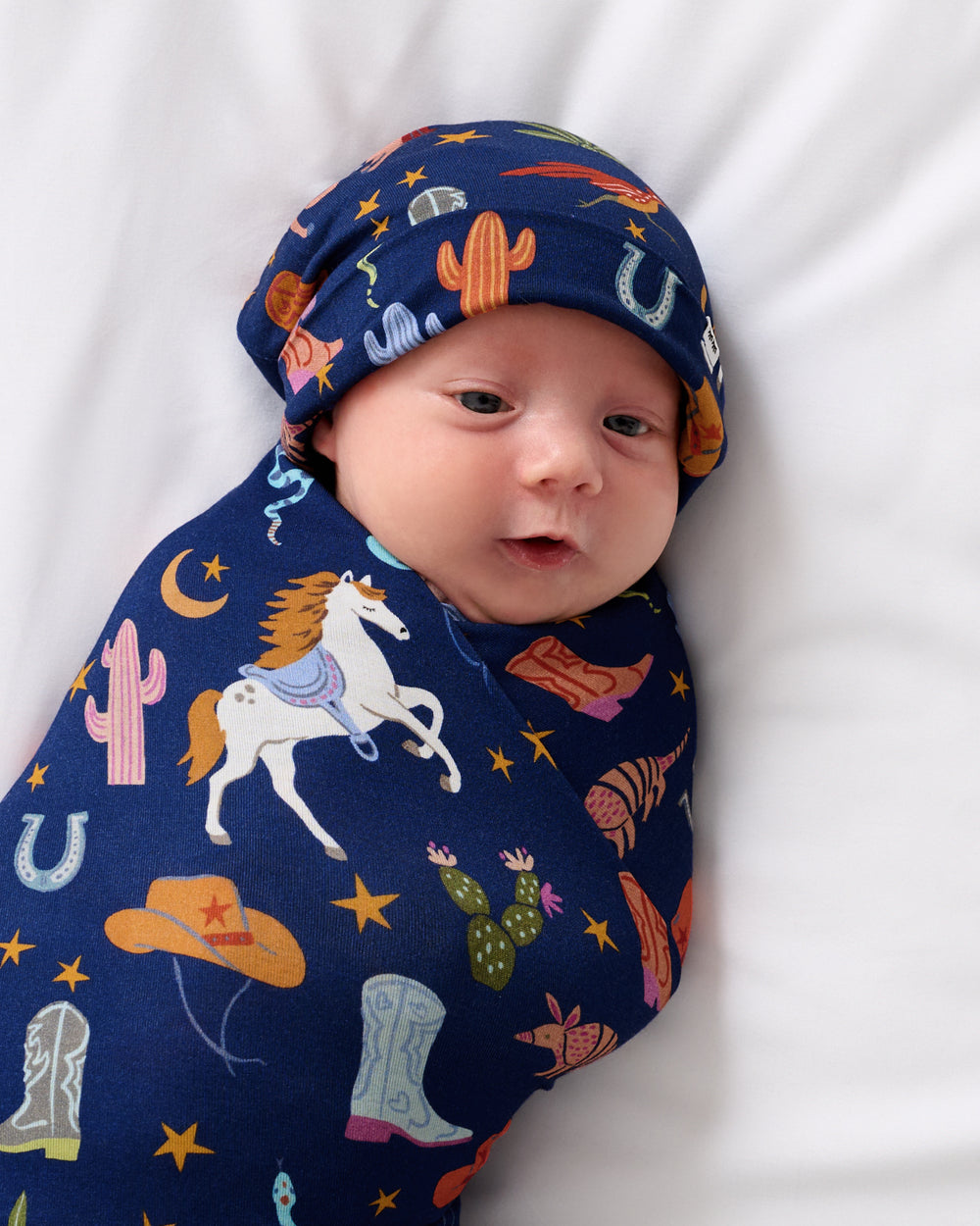 Close up of baby wrapped in the Blue Rancher Roundup Swaddle & Hat Set