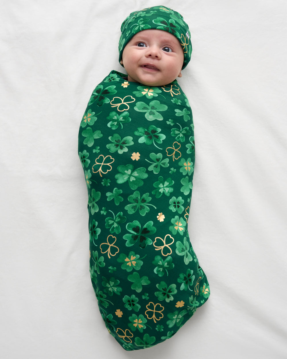 Aerial view of baby wrapped in the Clover Cuties Swaddle & Hat Set