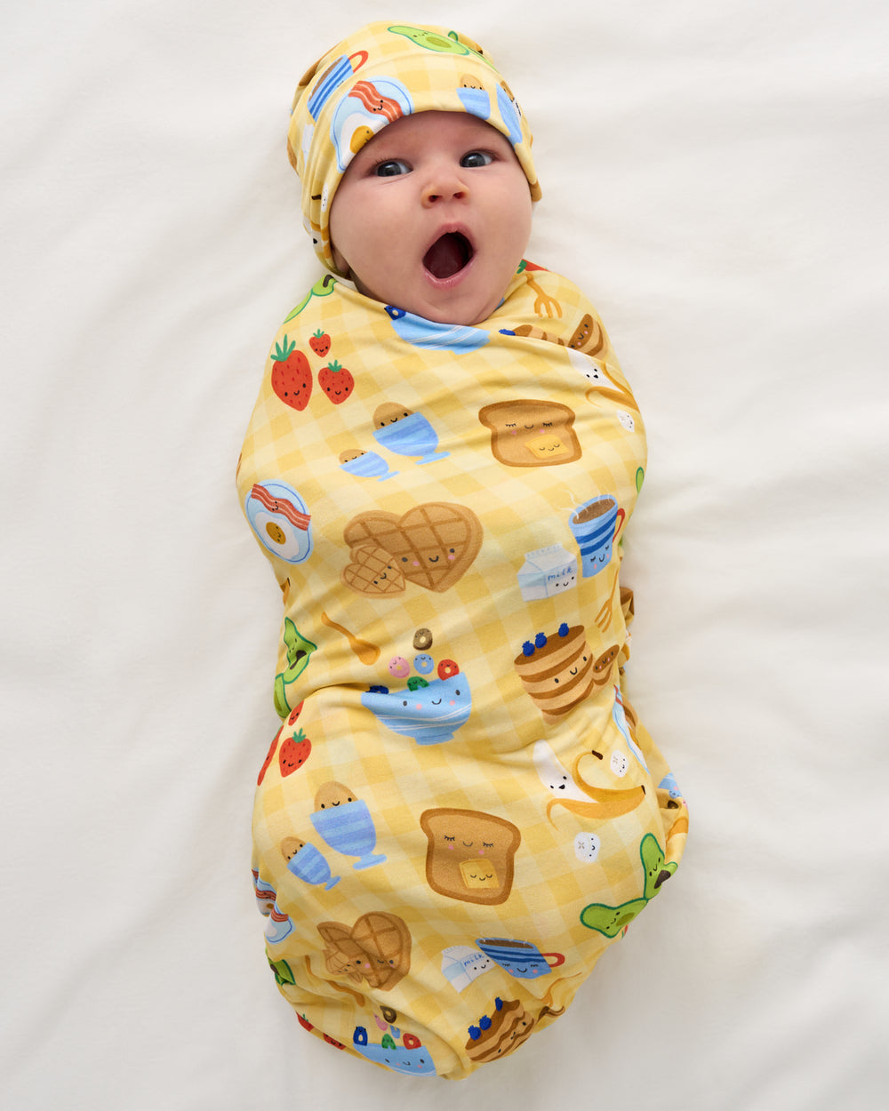 Aerial view of newborn swaddled in the Breakfast Bunch Swaddle & Hat Set