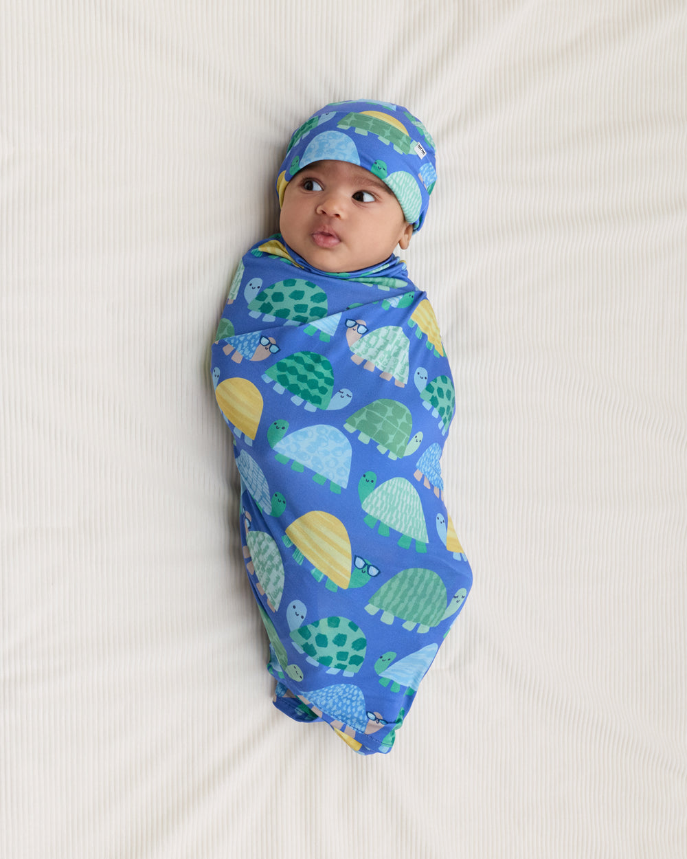 Ariel view of baby wearing the Shell Parade Swaddle & Hat Set
