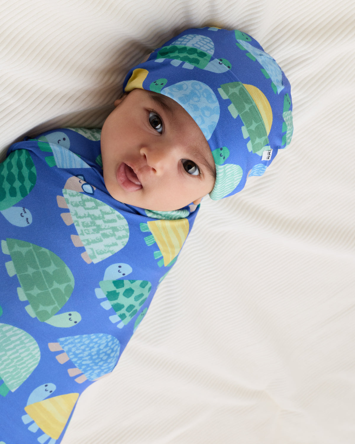 Close up of newborn swaddled in the Shell Parade Swaddle & Hat Set