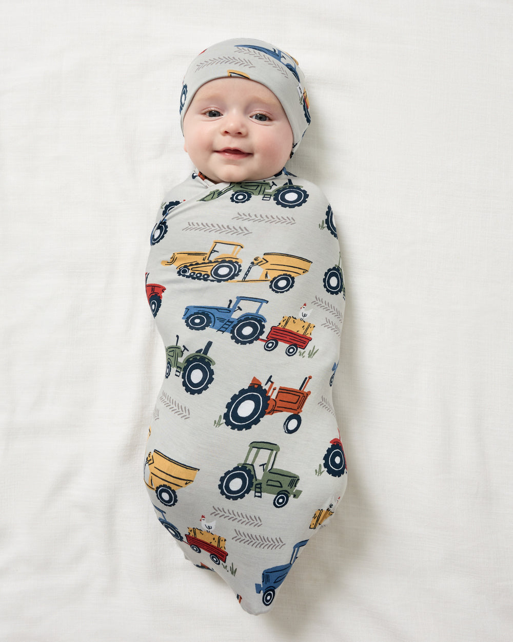Aerial view of baby boy swaddled in the Tractor Tales Swaddle & Beanie Set