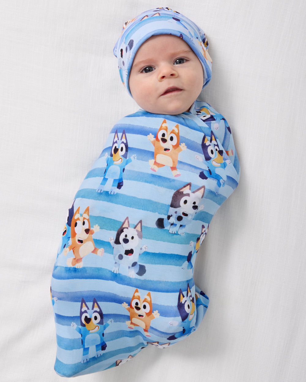 Aerial view of baby swaddled in the Bluey Dance All Day Swaddle & Hat Set