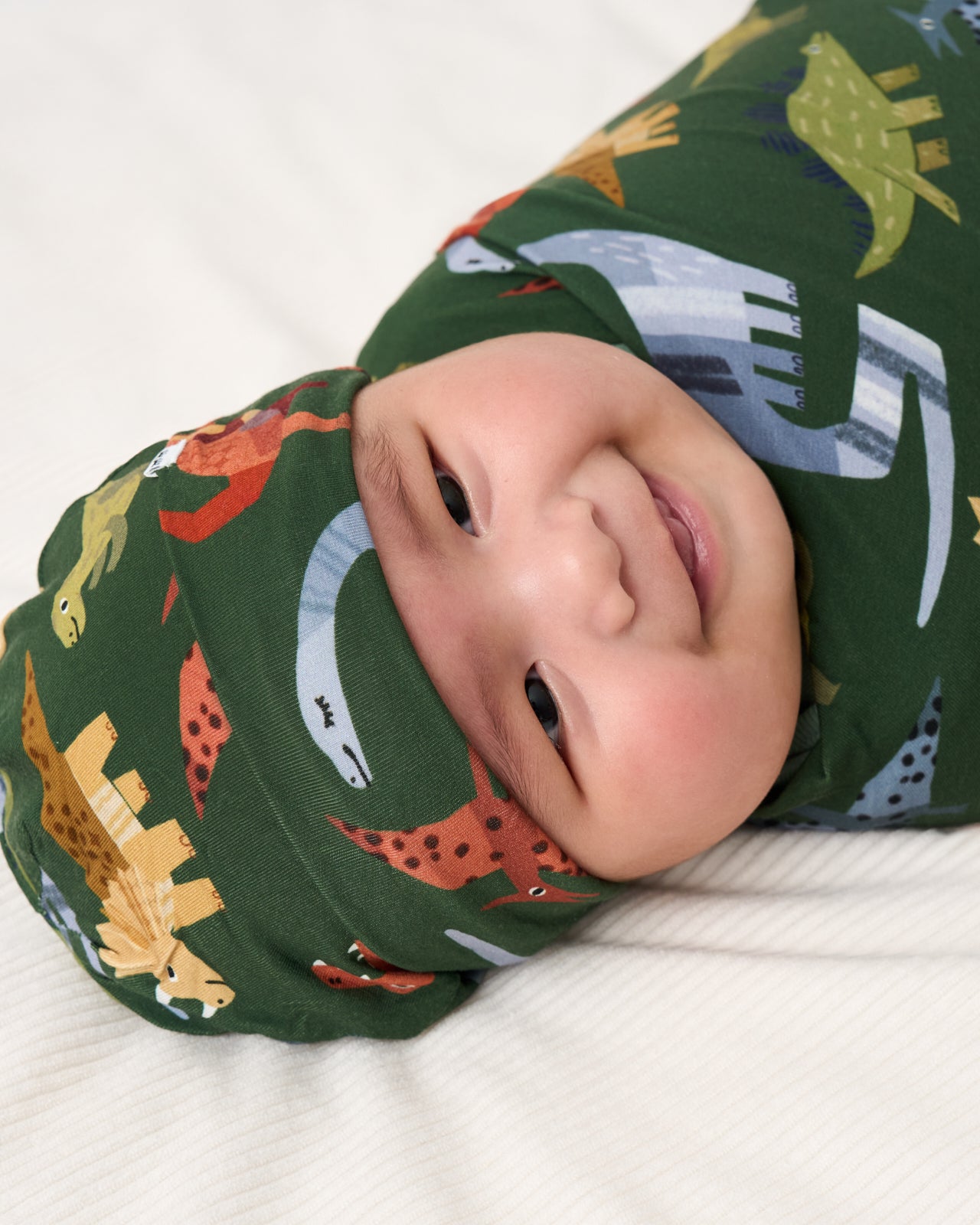 Close up of baby wearing the Green Roar & Explore Swaddle & Beanie Set