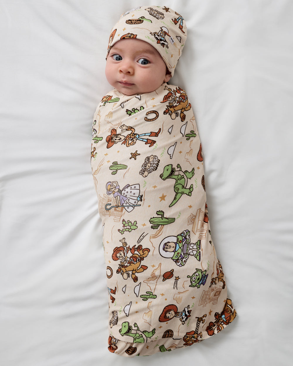 Aerial view of baby wearing the Disney & Pixar Woody's Wild West Swaddle & Beanie Set