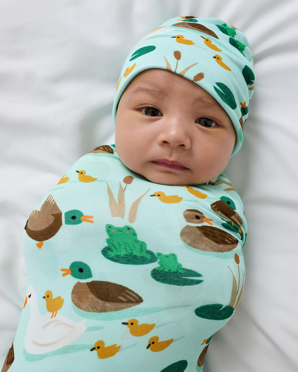 Close up of baby wearing the Puddle Jumpers Swaddle & Beanie Set