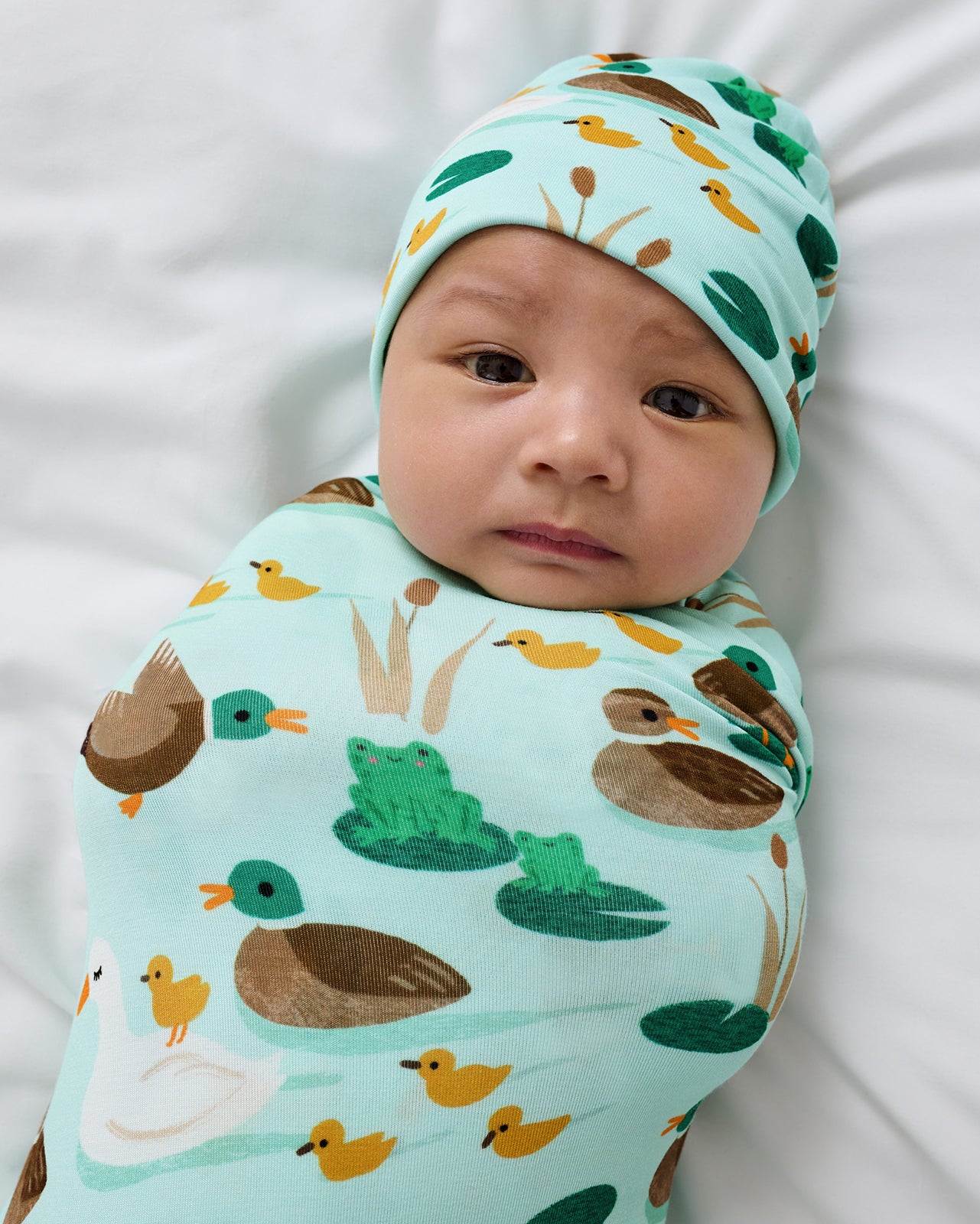 Close up of baby wearing the Puddle Jumpers Swaddle & Beanie Set