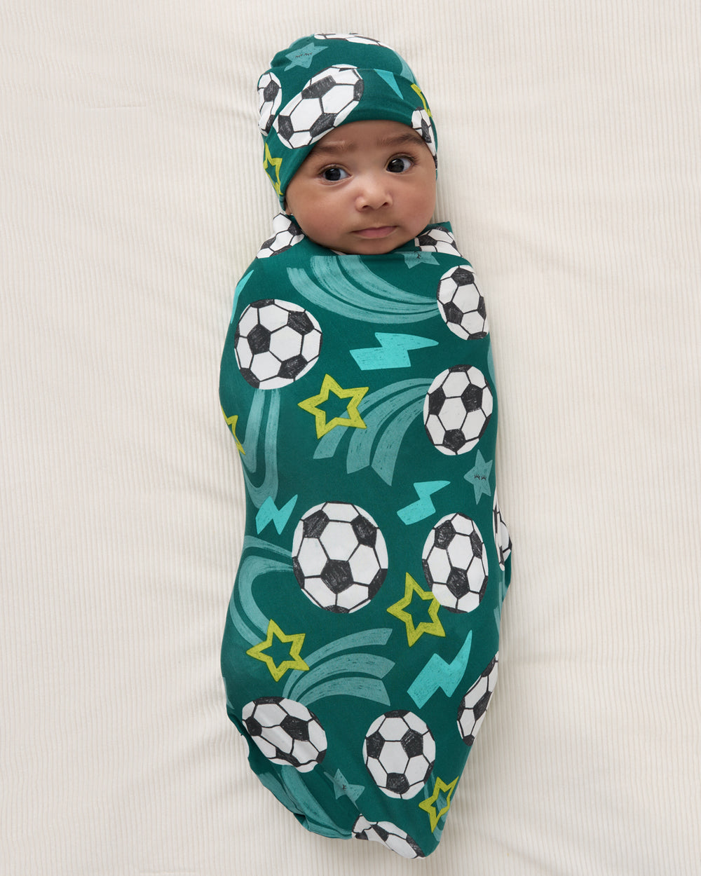 Aerial view of baby wearing the Soccer Stars Swaddle & Beanie Set