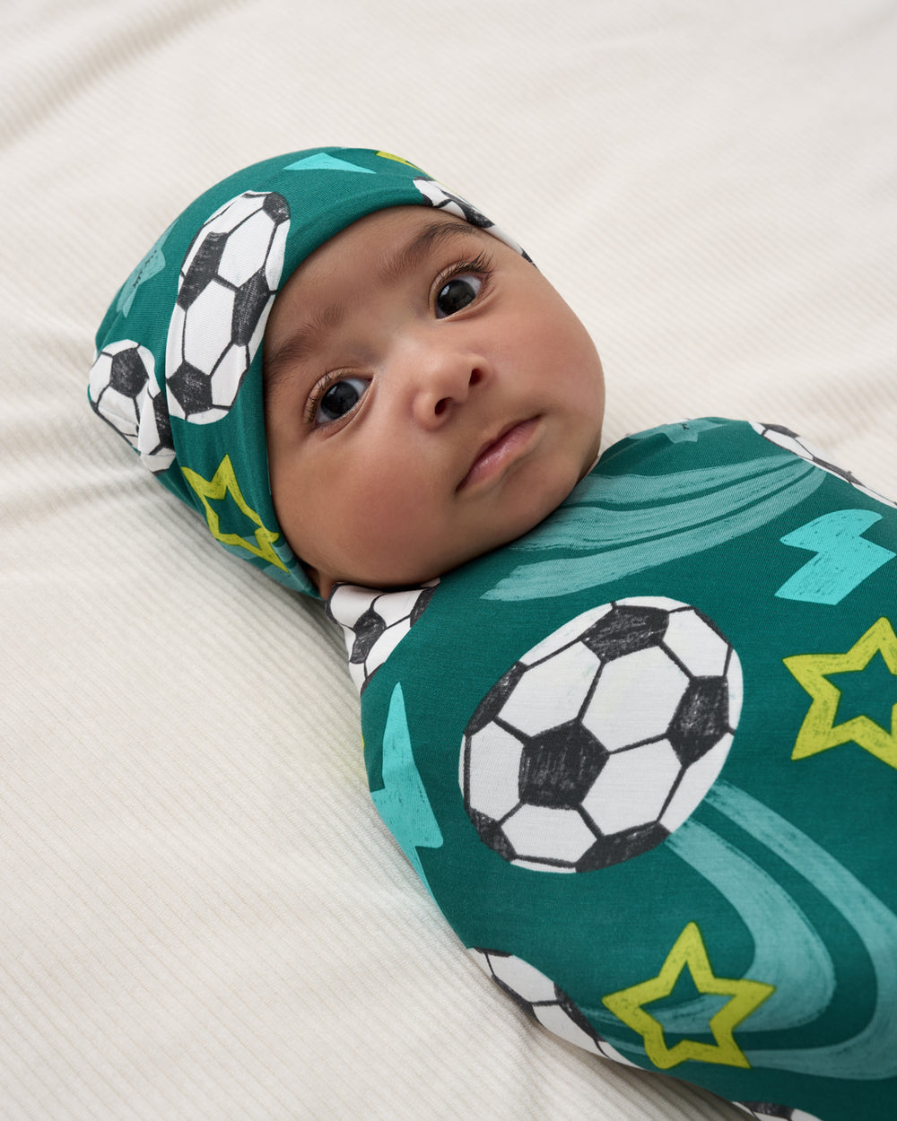 Close up of baby wearing the Soccer Stars Swaddle & Beanie Set