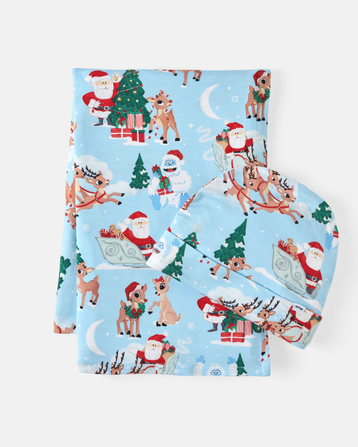 A folded light blue swaddling blanket printed with a festive Christmas pattern featuring Santa Claus, reindeer, Christmas trees, snowman, and wrapped gifts on a clean white background.