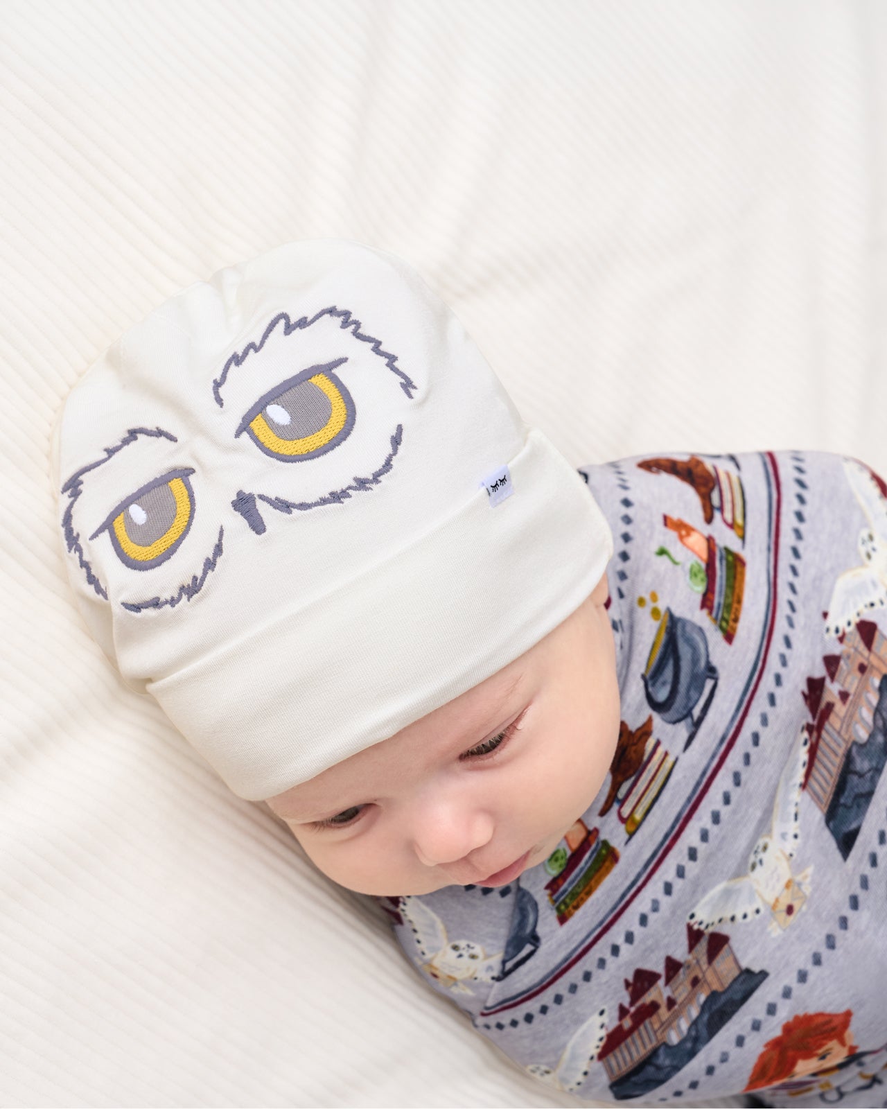 Close up of a newborn wearing the Harry Potter™ Spellbinding Studies Swaddle & Beanie Set