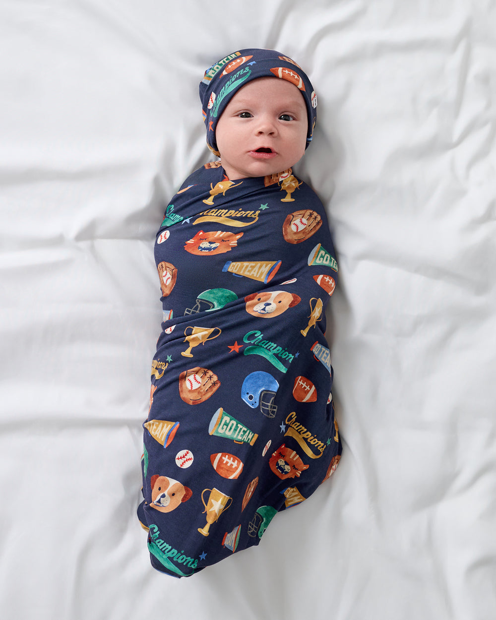 Aerial view of baby wrapped in the Team Spirit Swaddle & Beanie Set