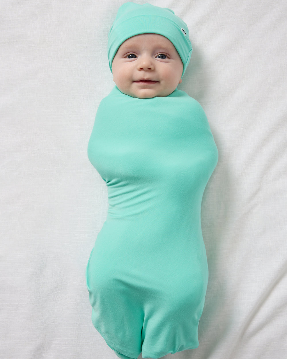 Aerial view of baby wearing the Ocean Mist Swaddle & Beanie Set