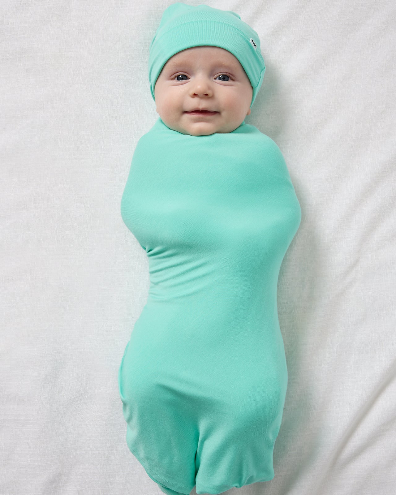 Aerial view of baby wearing the Ocean Mist Swaddle & Beanie Set