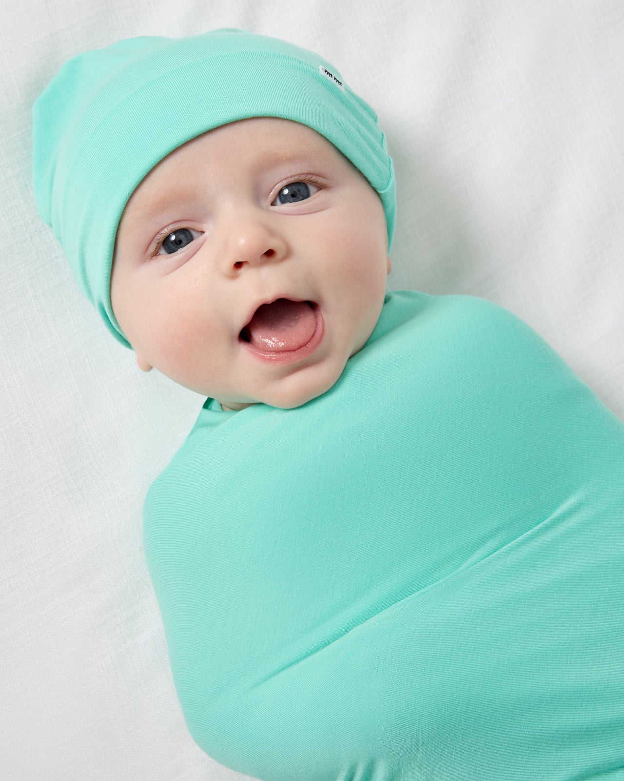 Close up of baby wrapped in the Ocean Mist Swaddle & Beanie Set