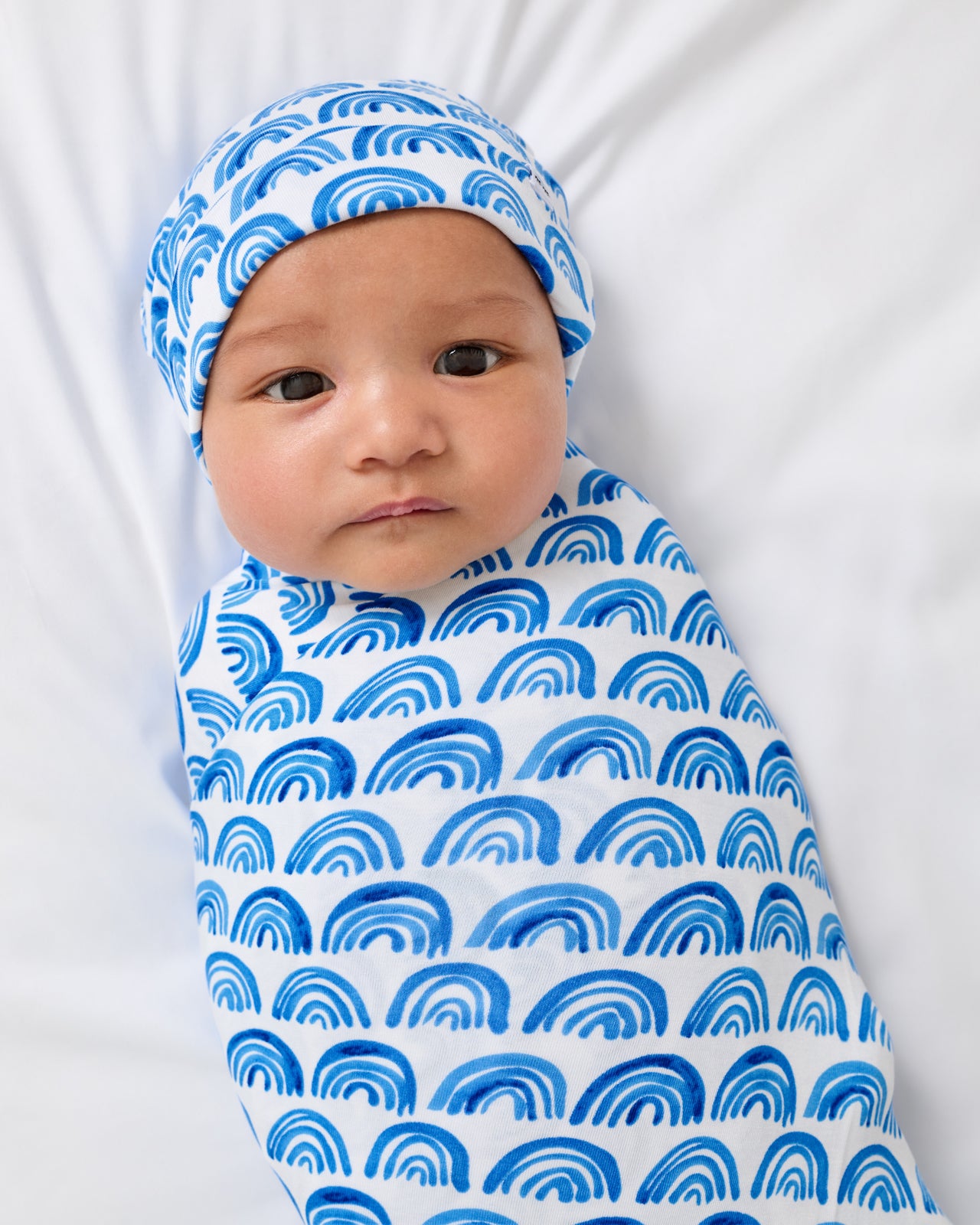 Close up of newborn wearing the Blue Rainbows Swaddle & Beanie Set