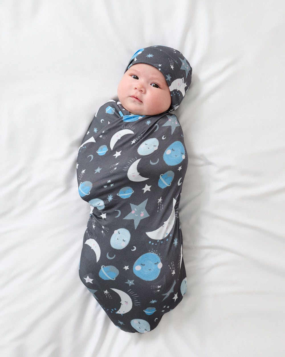 Baby wrapped in the Blue To The Moon & Back Swaddle & Beanie Set