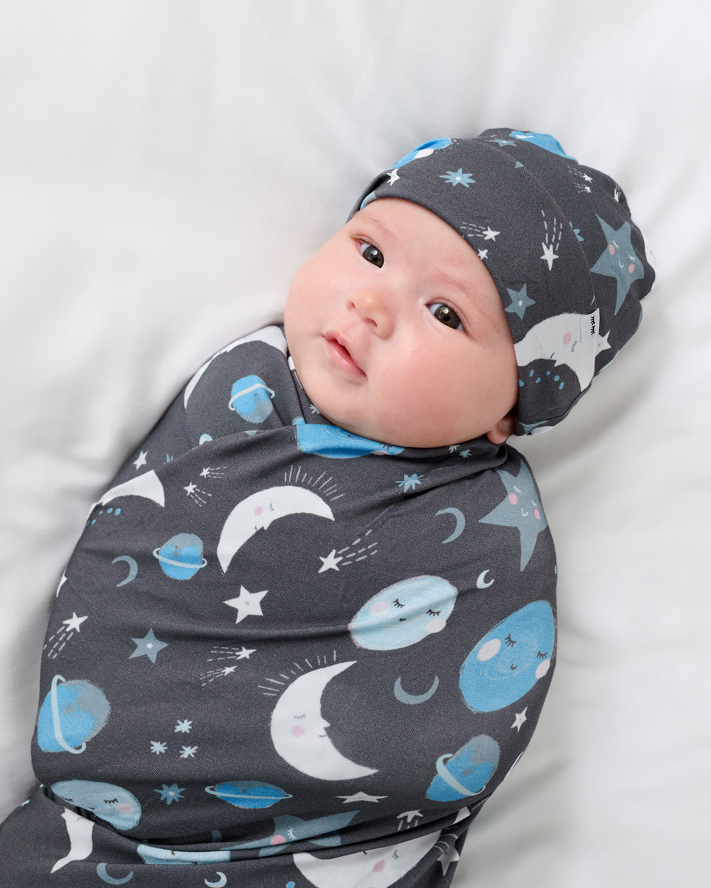 Close up of baby wearing the Blue To The Moon & Back Swaddle & Beanie Set