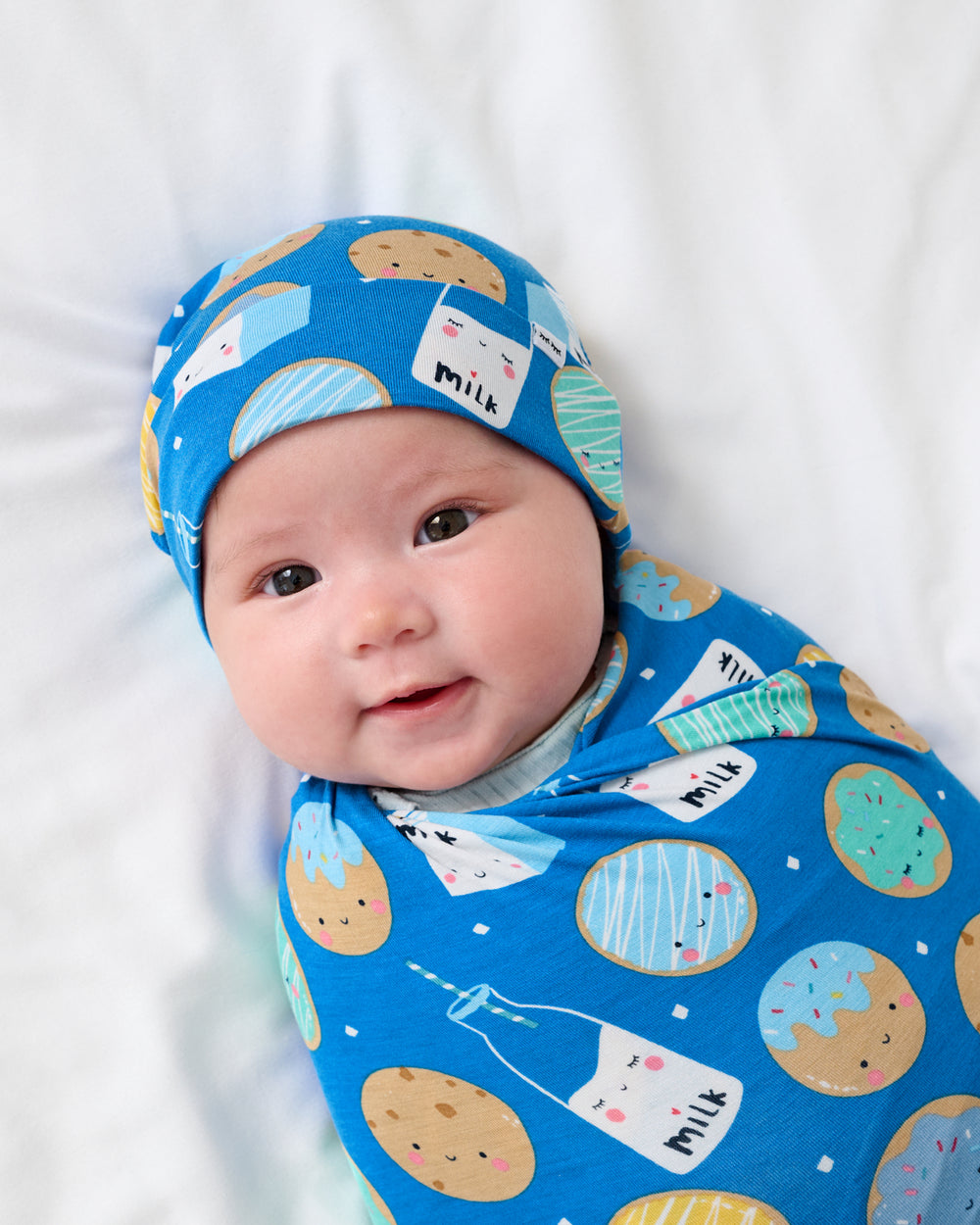 Close up of newborn swaddled in the Blue Cookies & Milk Swaddle & Beanie Set