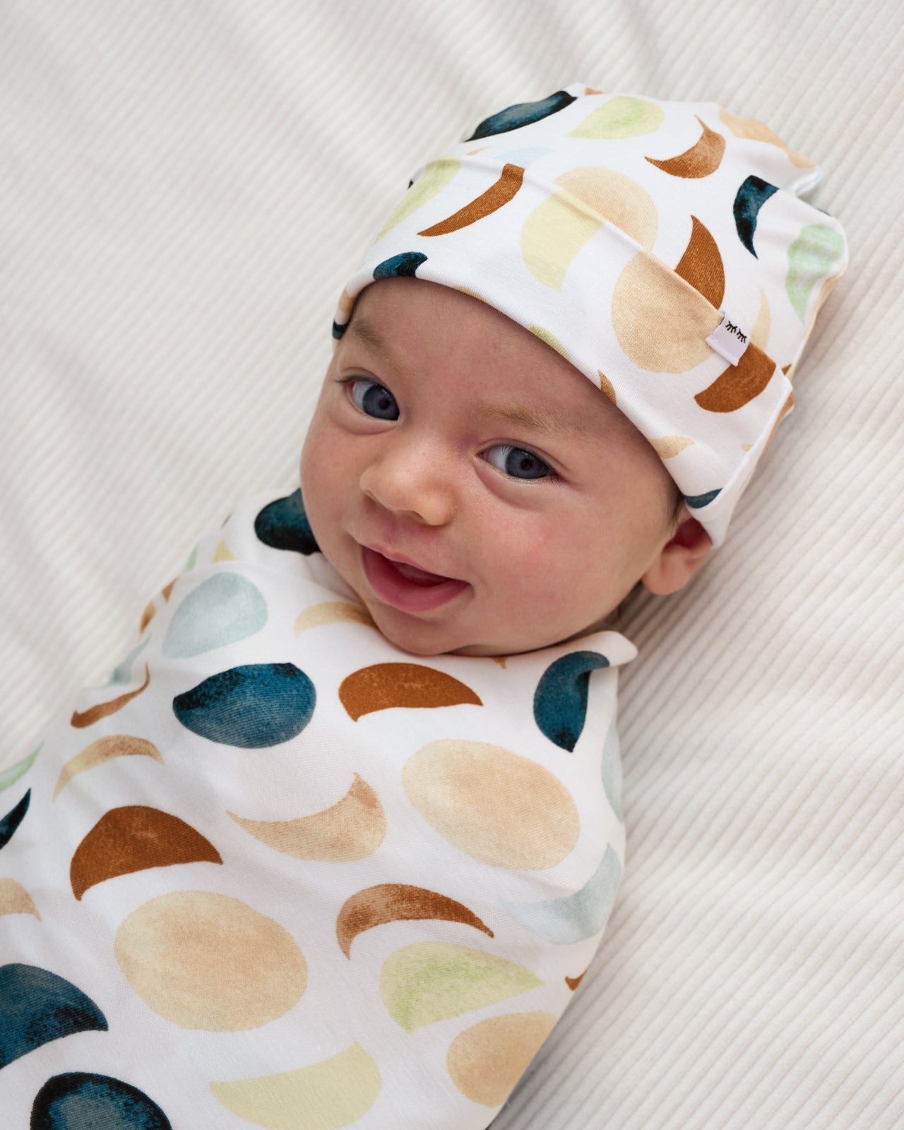 Close up of baby swaddled in the Luna Neutral Swaddle & Beanie Set