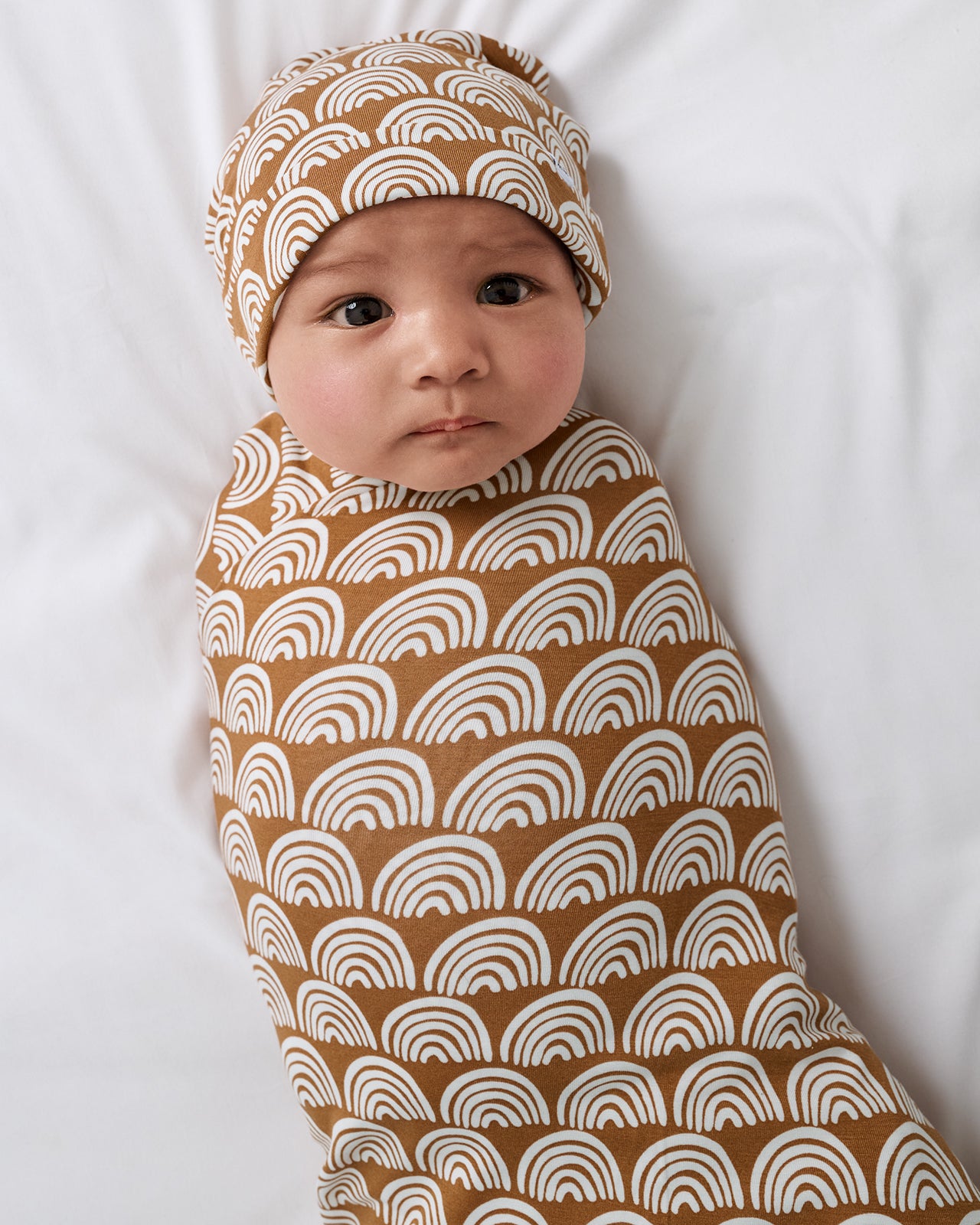 Newborn swaddled in the Rust Rainbows Swaddle & Beanie Set