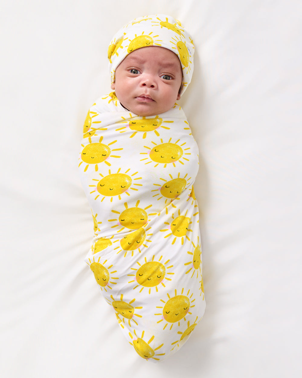Aerial view of baby wearing the Sunshine Swaddle & Beanie Set