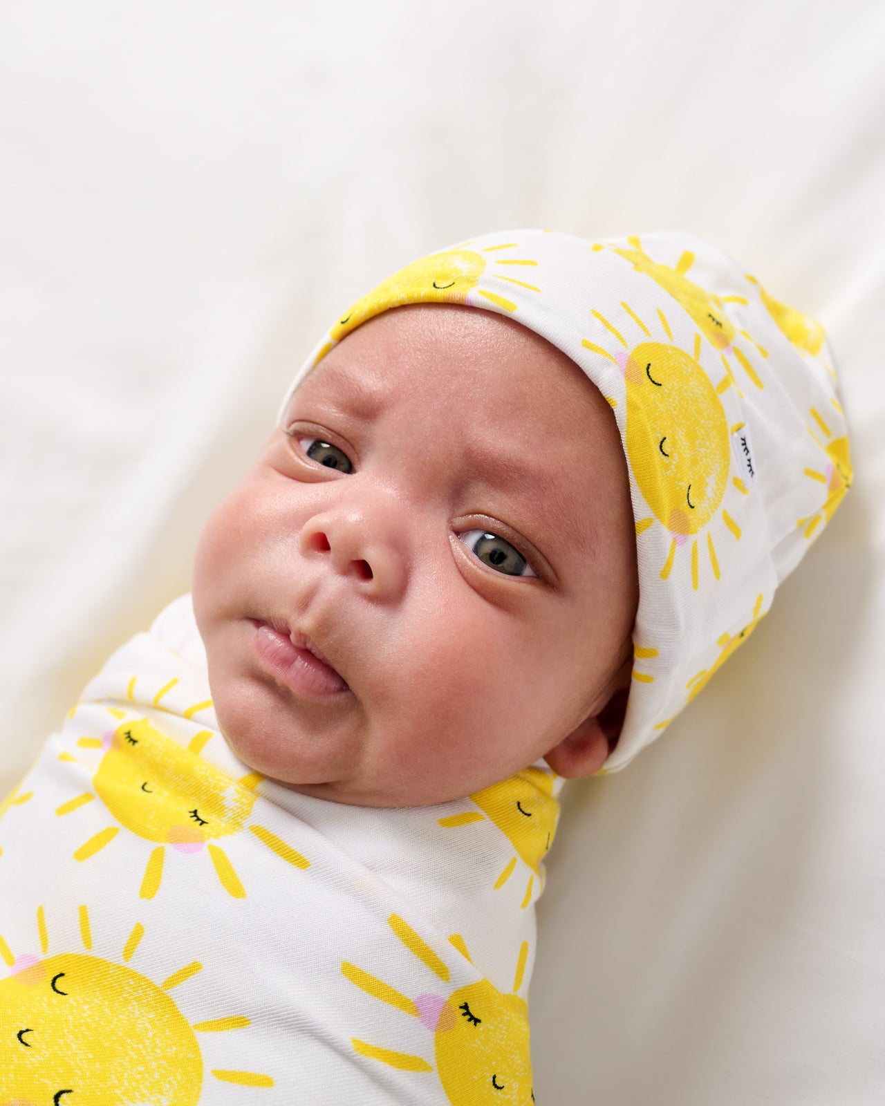 Close up of baby wrapped in the Sunshine Swaddle & Beanie Set