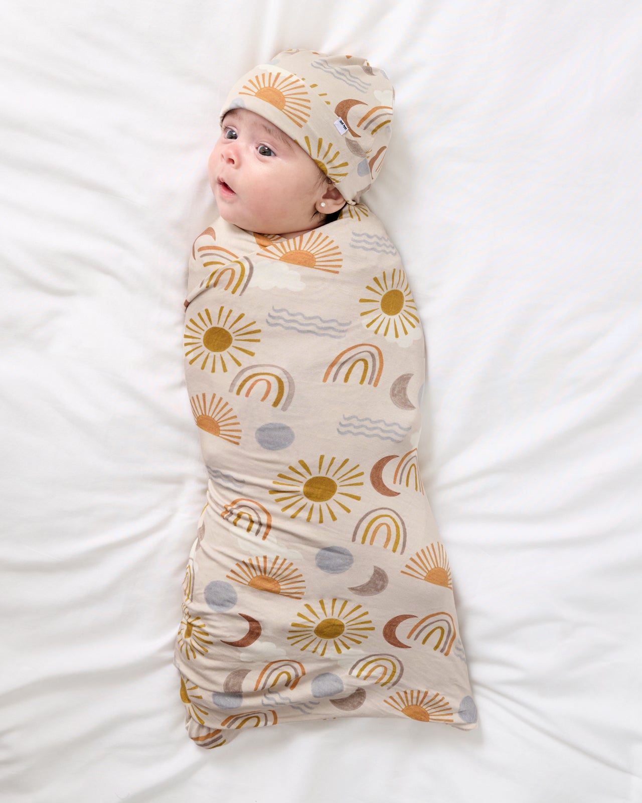 Aerial view of baby swaddled in the Desert Sunrise Swaddle & Beanie Set