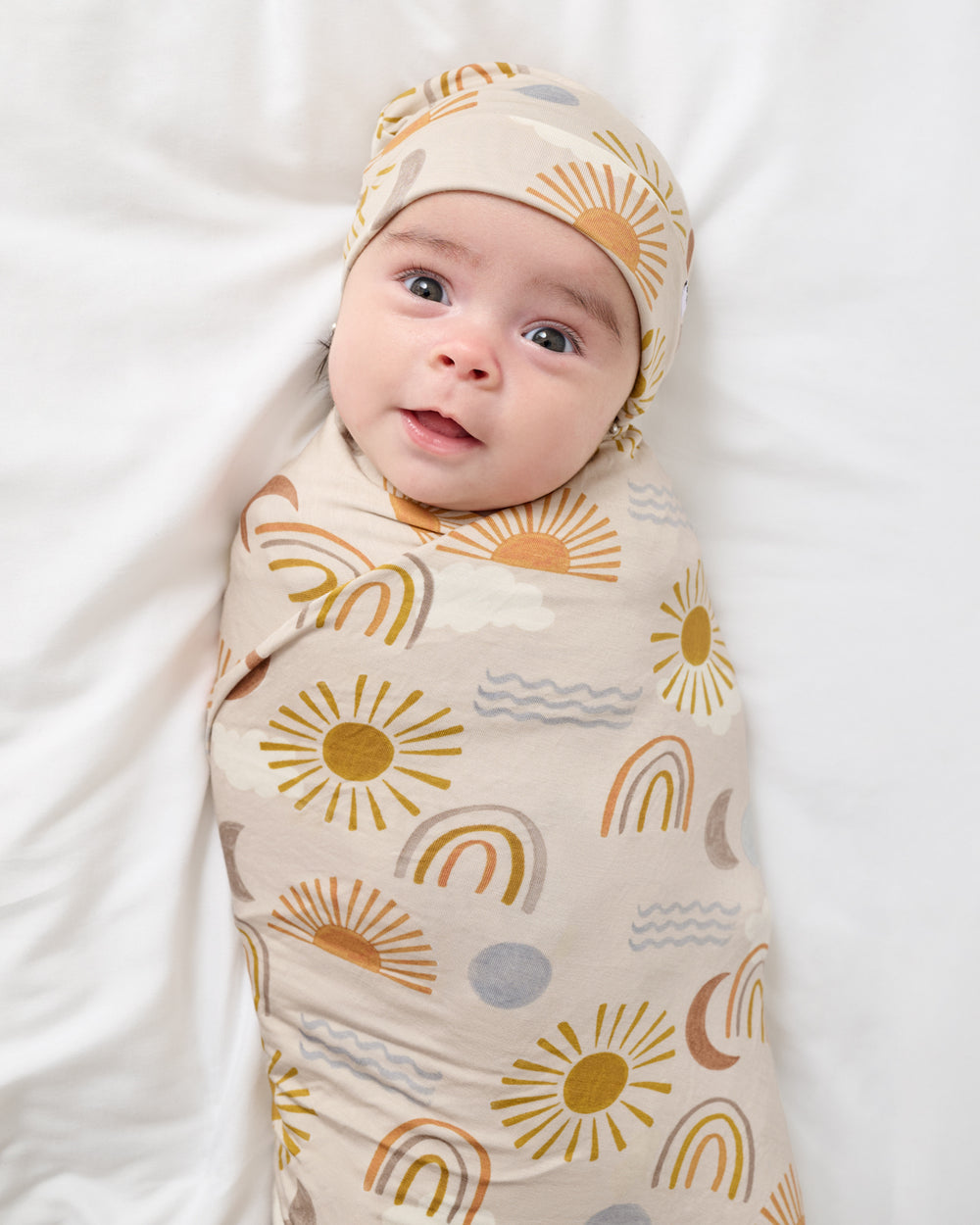 Newborn swaddled in the Desert Sunrise Swaddle & Beanie Set