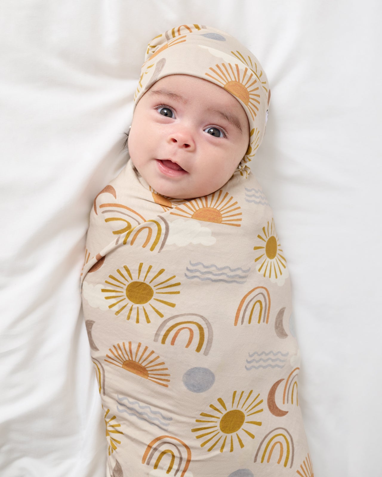Newborn swaddled in the Desert Sunrise Swaddle & Beanie Set