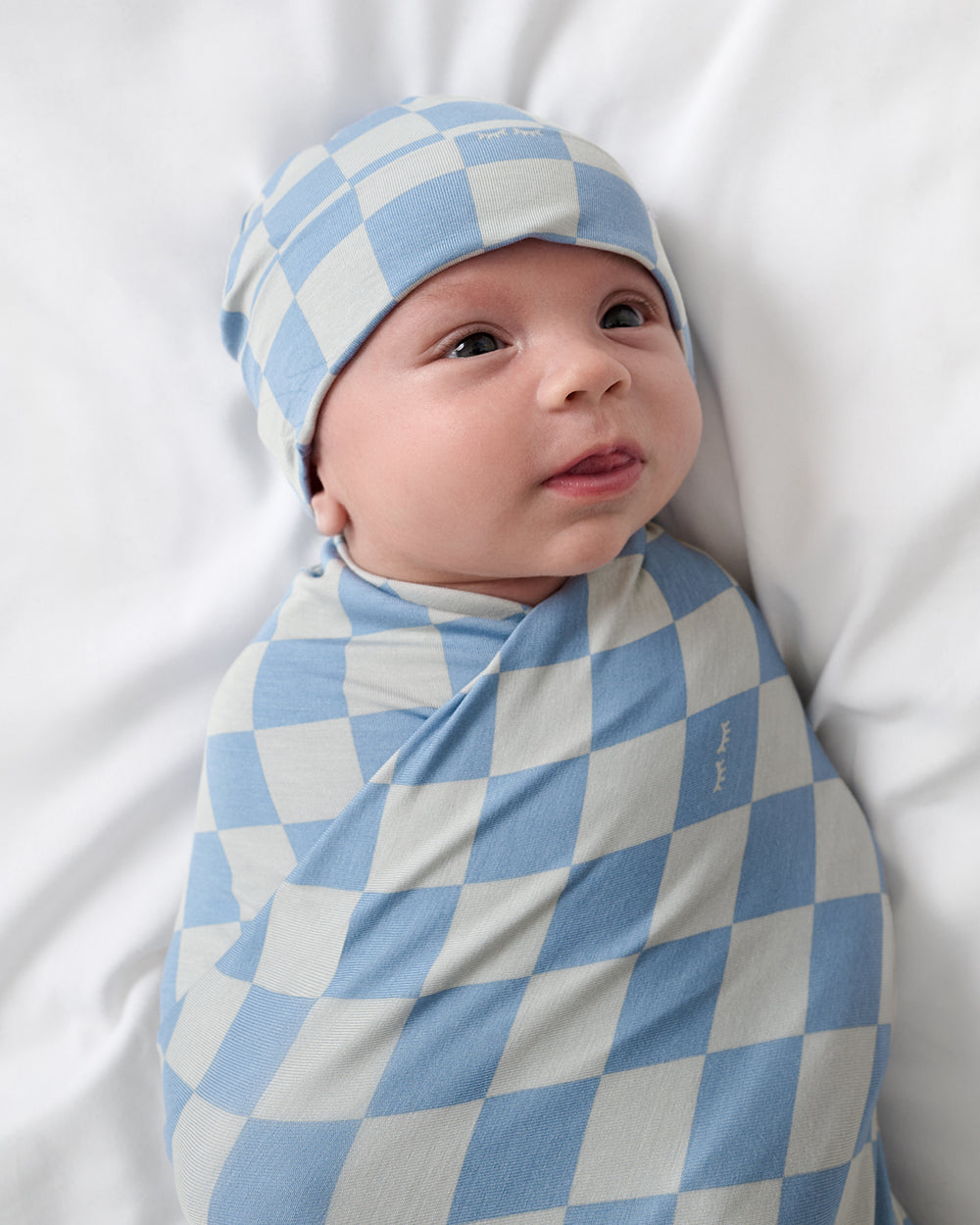 Close up of baby swaddled in the Dusk Blue Checks Swaddle & Beanie Set