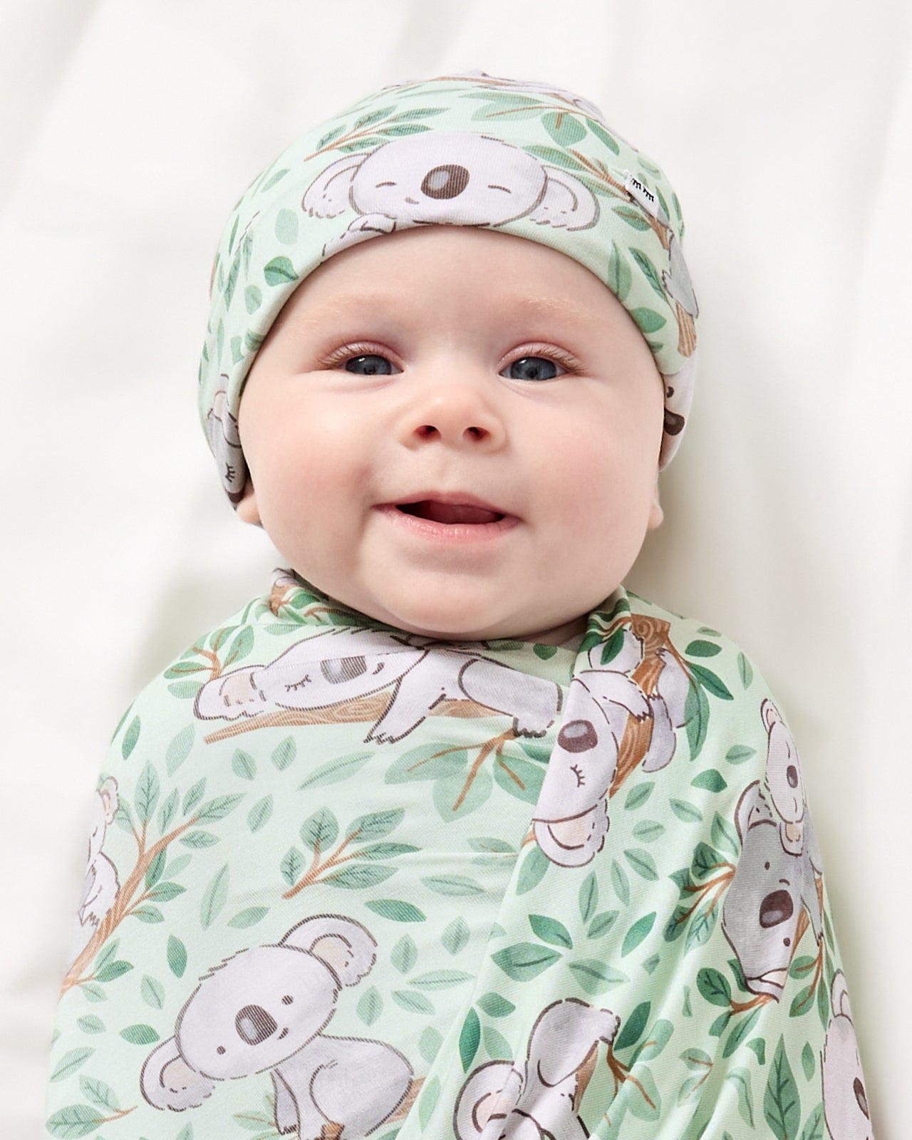 Close up of newborn wrapped in the Koala Cuddles Swaddle & Beanie Set