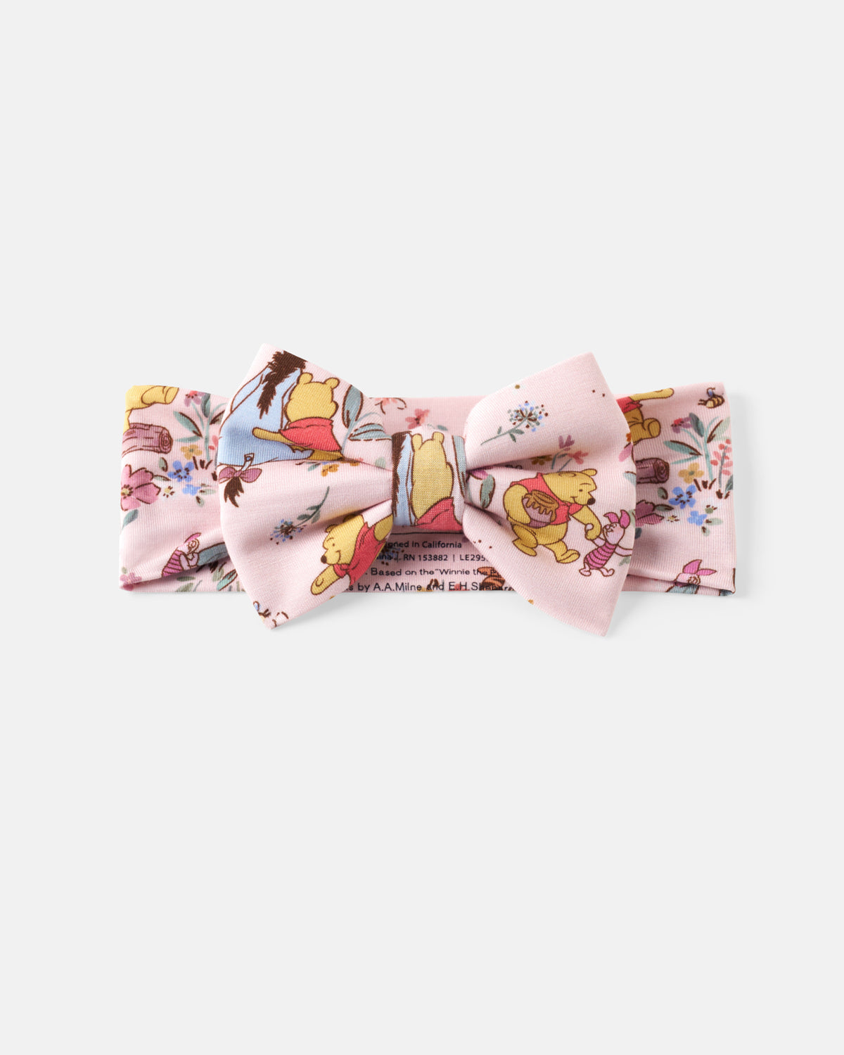 A light pink fabric accessory set featuring a bow tie and matching bandana with a whimsical cartoon character print, displayed on a clean light gray background.