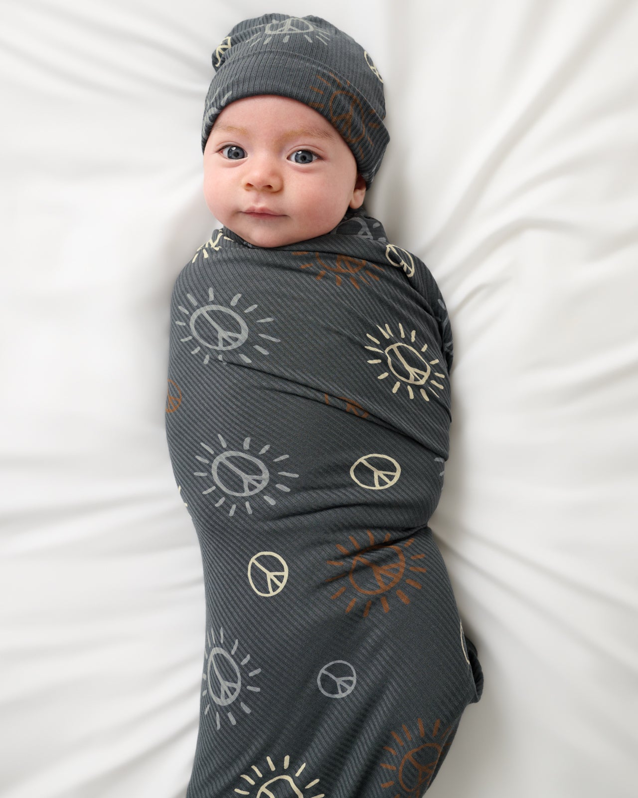 Aerial view of baby wrapped in the Peace & Love Ribbed Swaddle & Beanie Set